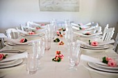 White place settings with roses and linen napkins on white wooden table