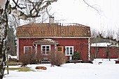 View of falu red house with white windows in snowy garden