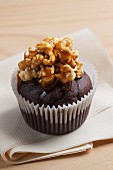 A chocolate cupcake topped with popcorn and caramel