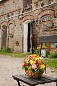 Flower arrangement on garden chair in front of stables with brick façade