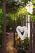 Heart-shaped wreath hanging on open garden gate