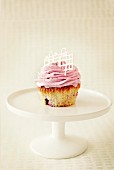 A blackberry cupcake on a cake stand