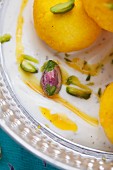 Milk balls with saffron in yoghurt with pistachios and sugar syrup