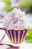 A cupcake decorated with lilac flowers