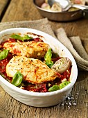 Chicken breast with tomatoes and onions in a baking dish