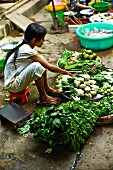 A girl selling vegetables at a market in Saigon (Vietnam)