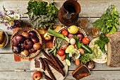 A bird's-eye view of a table laid with onions, a jug of must, vegetables, fruit, bacon, bread and snack sausages, Austria
