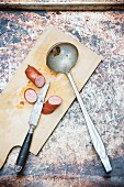 Sliced sausage with a knife and a soup ladle on a chopping board