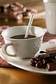 A cup of black coffee with chocolate on the saucer