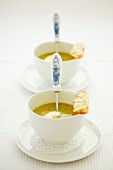Two cups of pea soup with a dollop of cream and a cheese crostini