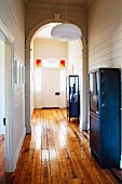 Hauseingang mit Rundbogen und weißer Holzverkleidung, blaue Vintage Metallschränke auf rustikalem Dielenboden