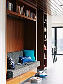 Wooden shelves with sofa in reading niche and textiles in shades of blue