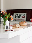 Breakfast place setting on island counter in front of vintage street sign on fitted kitchen counter
