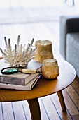 Books, tealight holders and white coral decorating wooden side table