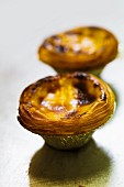 Frisch gebackene Custard Pies (Eiercremetörtchen, England) im Alubackförmchen