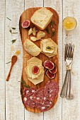 A platter of cheese and cured meats with crackers, honey and figs