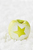 An apple in the snow decorated with a star