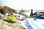 A picnic on a beach with grapes, cheese, bread and wine