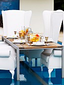 Festively set table and throne-like, white, upholstered armchairs on special floor insert in swimming pool