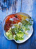 A plate of salad featuring various different coloured tomatoes, cucumber and sheep's cheese