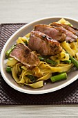 Duck breast on a bed of tagliatelle with green asparagus