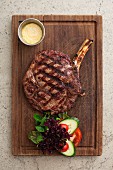 A grilled beef chop on a wooden board (seen from above)