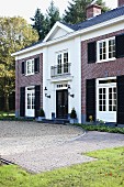 Two-storey manor house with symmetrical brick facade and front entrance in white-rendered central section