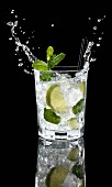 A splashing glass of vodka lemon against a black background