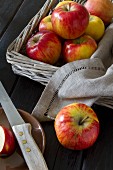 Apples in a rectangular basket with a linen serviette, one apple next to the basket