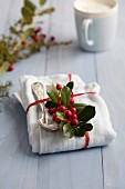 A napkin and an old-fashioned spoon decorated with holly