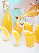 Selbstgemachte Orangen-Ingwer-Limonade in Gläser einschenken
