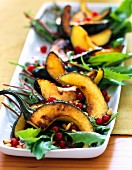 Roast acorn squash with dandelion leaves and pomegranate seeds