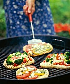 Pita bread pizzas being cooked on a barbecue