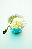 A bowl of grated Emmental cheese with a spoon
