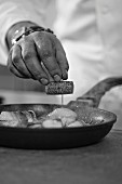 Koch bereitet Fischspiesse zu (Schwarz-Weiß-Aufnahme)