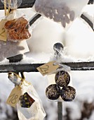 Small bags of biscuits hanging on snowy fence as Advent calender