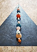 Black triangle and string of colourful wooden beads with candleholders on chipboard dining table