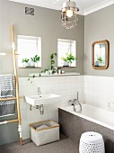 Renoviertes Bad - Waschbecken und Badewanne vor halbhoch gefliester Wand, darüber hellgraue Wandfläche