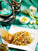 Fried scallops on wheat noodles with green curry paste, garlic butter and spring onions (Japan)