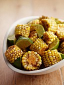 Grilled corn cobs with lime wedges