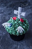 A gruesome cupcake for Halloween decorated with a grave