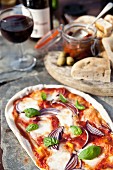 A stone oven pizza with focaccia, antipasti and wine in the background