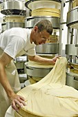 A dairy worker making cheese – creating a wheel
