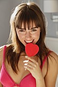 A young woman holding a heart-shaped lollipop