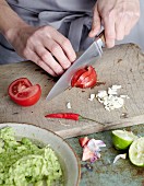 Guacamole being made: tomatoes, chilli and garlic being chopped