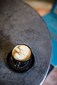 Kaffee mit Milchschaum auf Bistrotisch