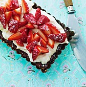 A cake with chocolate glaze, vanilla cream and strawberries
