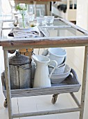 Various kitchen utensils and crockery on serving trolley in kitchen