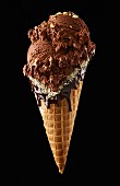 A chocolate ice cream cone with nuts