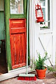 Hurricane lamp and broom outside front door painted in bright green and orange